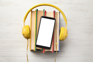 Photo of Books with modern headphones and smartphone on white wooden background, top view. Space for design