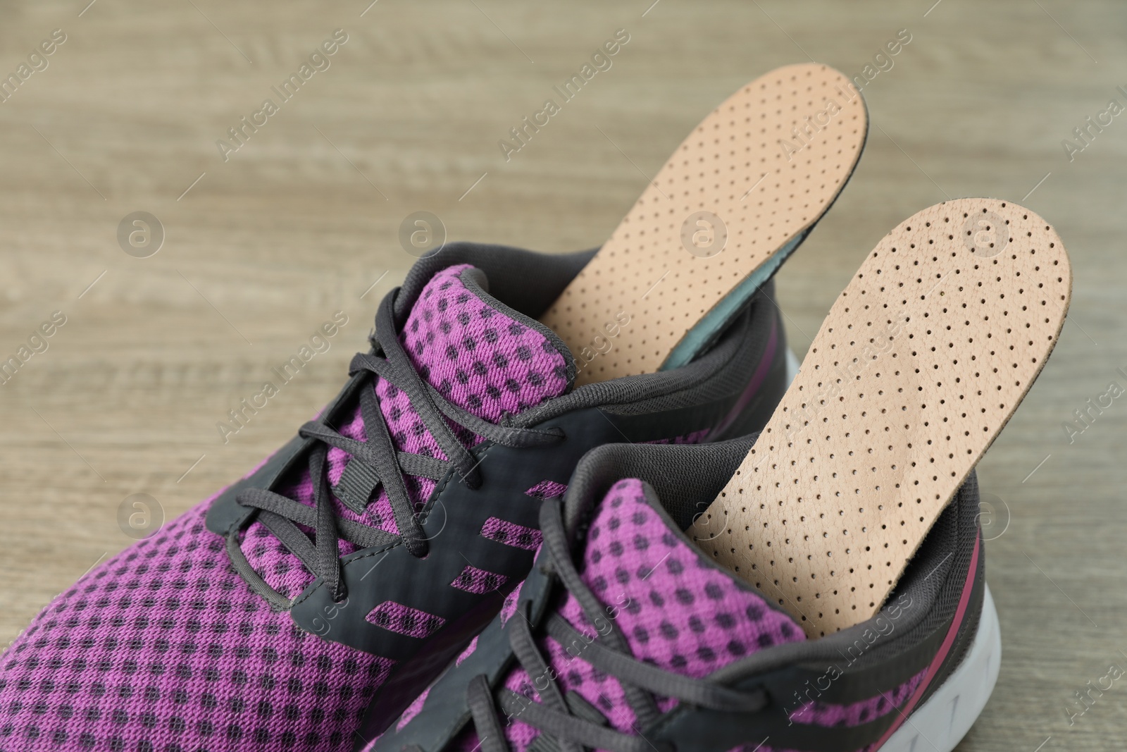 Photo of Orthopedic insoles in shoes on floor, closeup