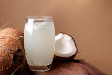 Photo of Glass of coconut water and nuts on wooden table, space for text