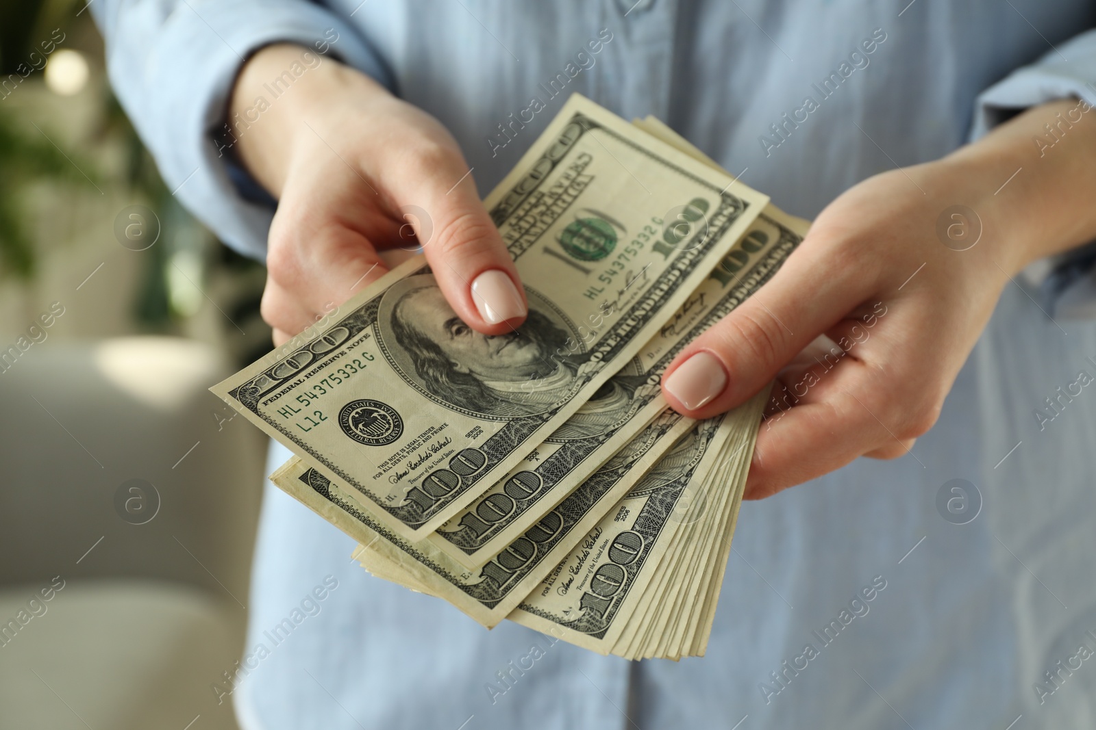 Photo of Money exchange. Woman counting dollar banknotes on blurred background, closeup