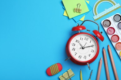 Photo of Flat lay composition with alarm clock and different stationery on light blue background, space for text. School time