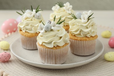 Tasty Easter cupcakes with vanilla cream and candies on table