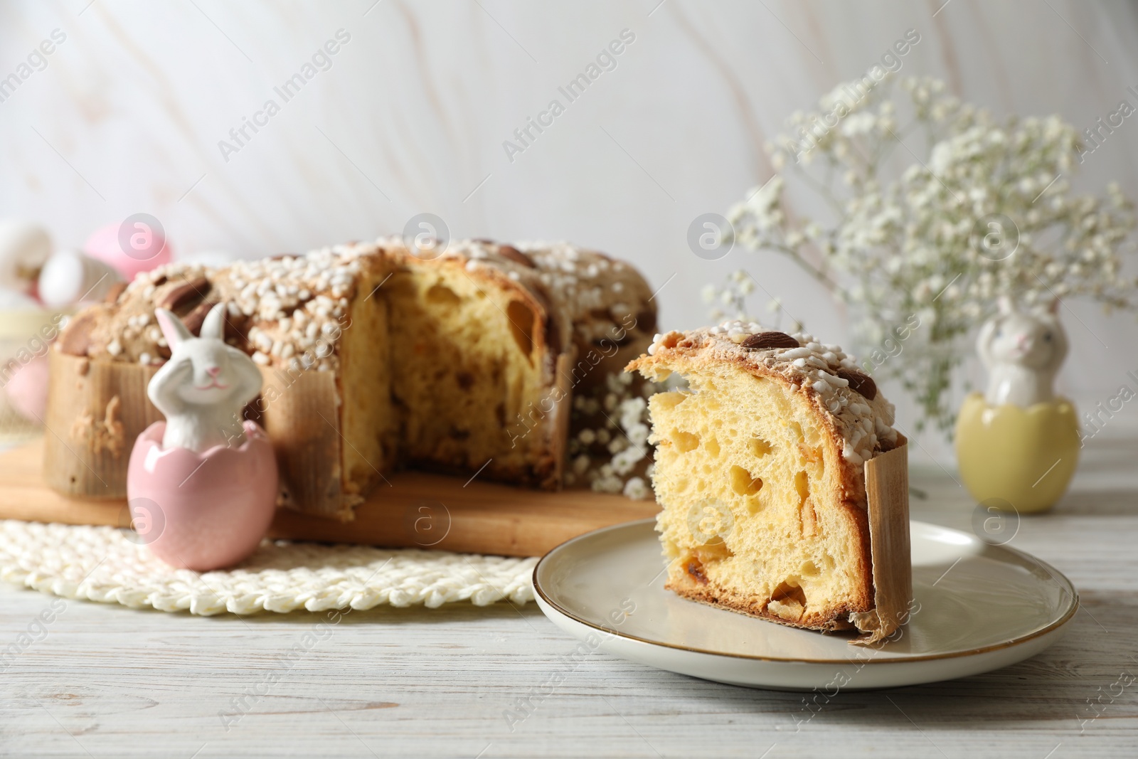 Photo of Delicious Italian Easter dove cake (traditional Colomba di Pasqua) and festive decor on white wooden table