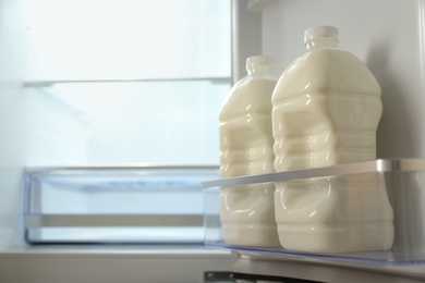 Photo of Gallons of milk in refrigerator, closeup. Space for text