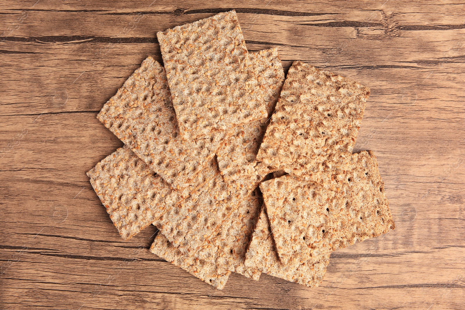 Photo of Fresh crunchy crispbreads on wooden table, flat lay