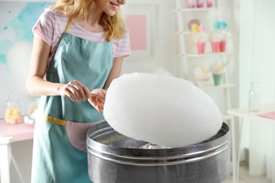 Photo of Woman making cotton candy using modern machine indoors, closeup