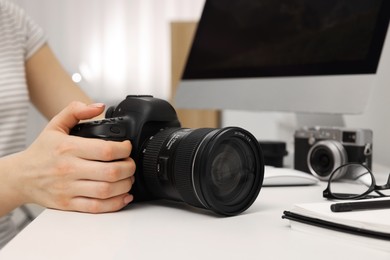 Photographer with camera at white table indoors, closeup