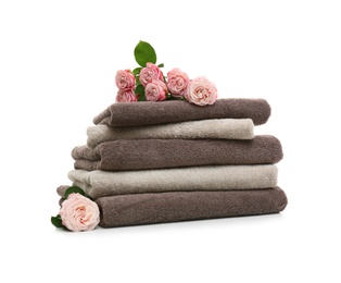 Stack of clean folded towels with flowers on white background