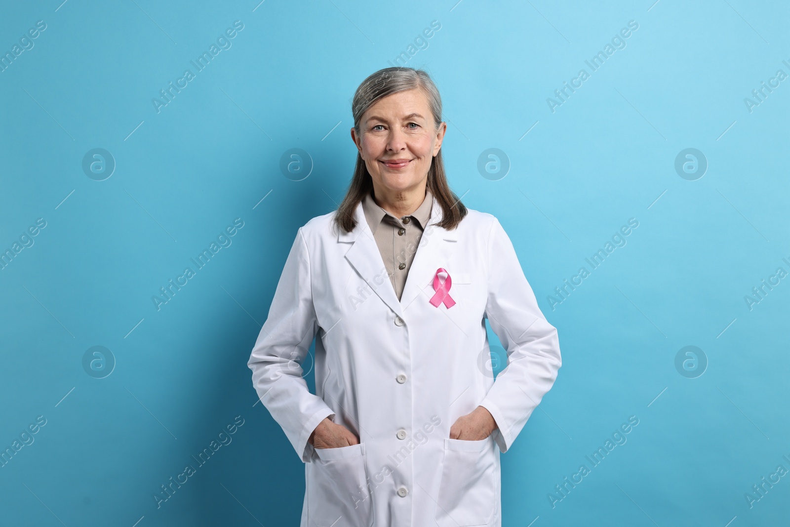 Photo of Mammologist with pink ribbon on light blue background. Breast cancer awareness