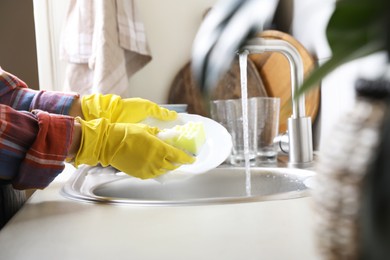 Photo of Woman washing plate in kitchen sink, closeup