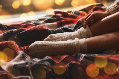 Woman in knitted socks on warm plaid, closeup