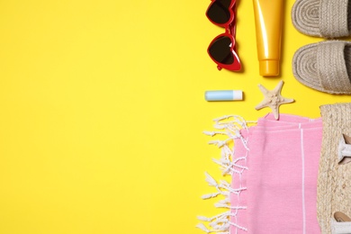 Flat lay composition with beach accessories on yellow background. Space for text