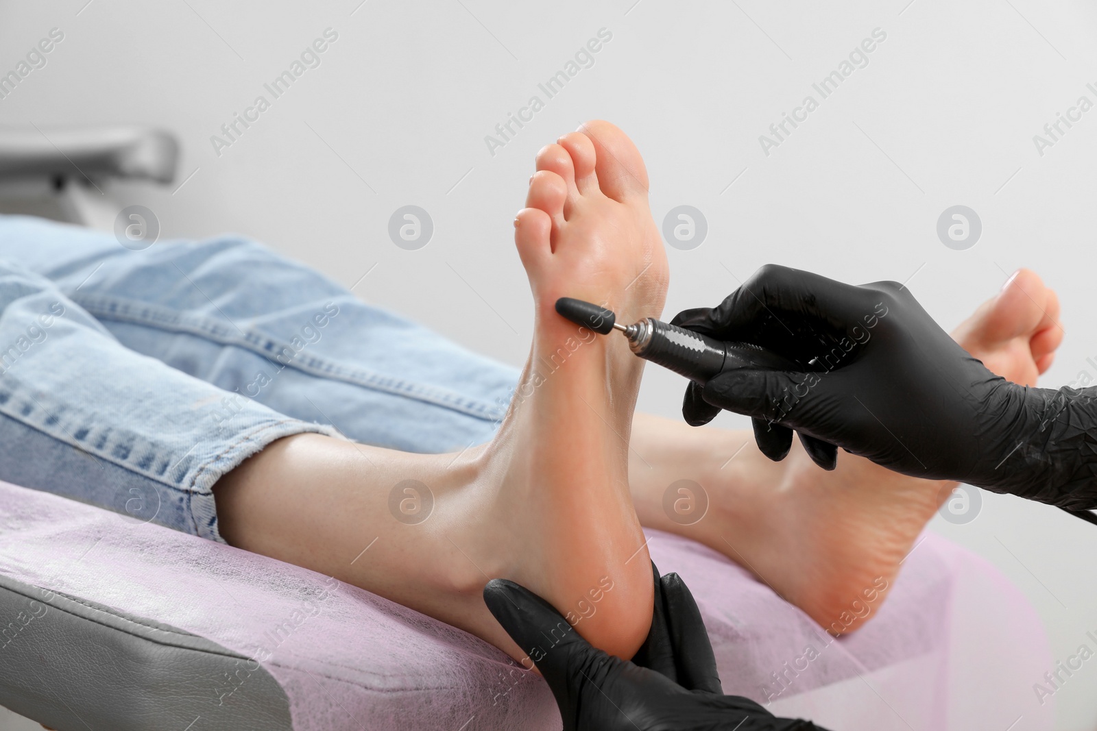 Photo of Professional master making hardware pedicure for client in beauty salon, closeup