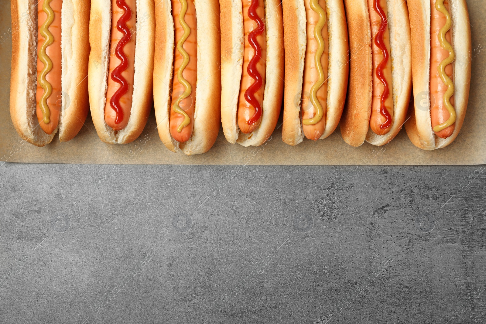 Photo of Tasty fresh hot dogs on grey background, top view. Space for text