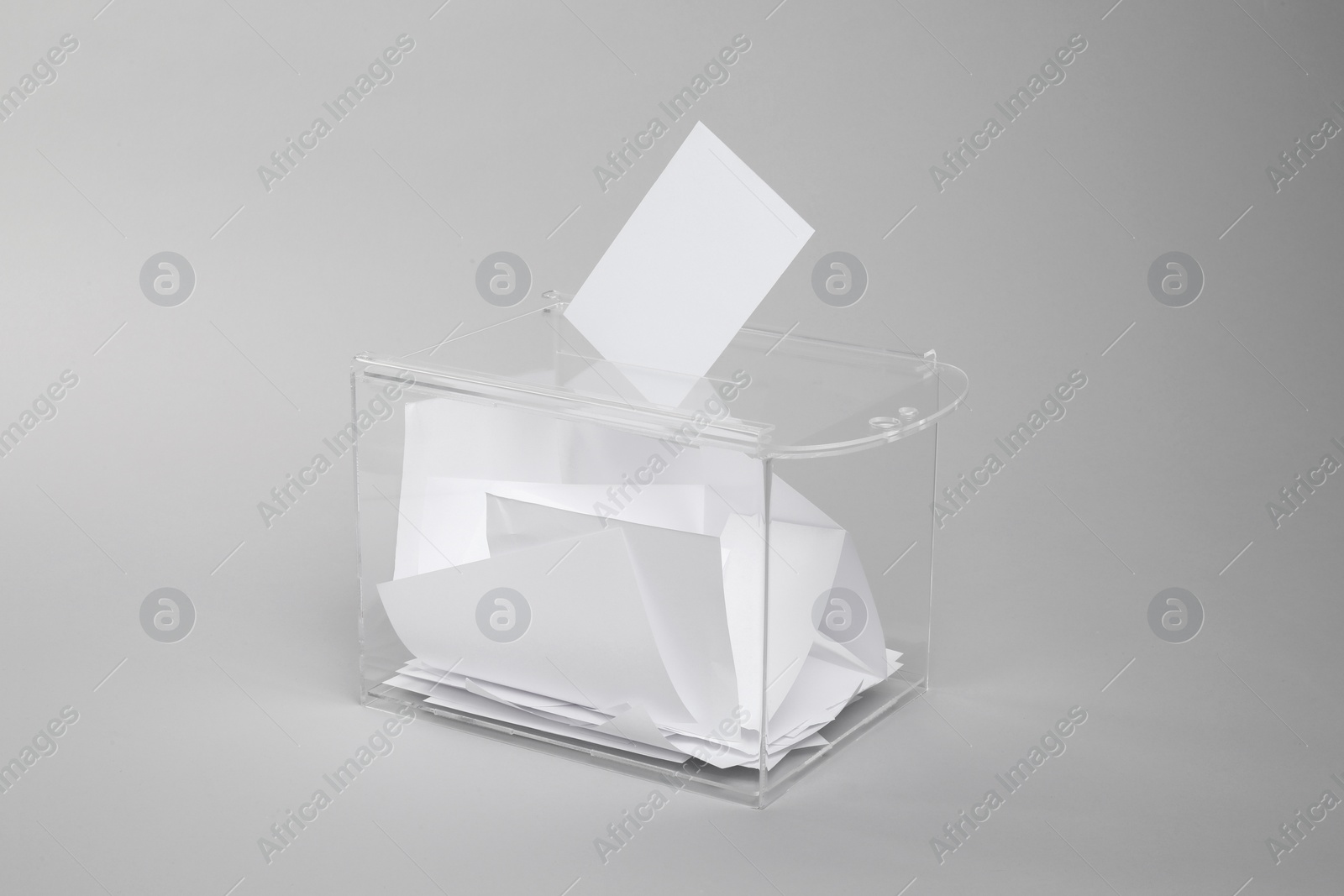 Photo of Ballot box with votes on light grey background. Election time