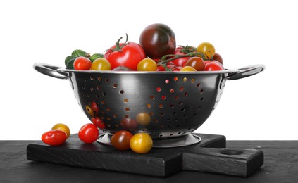 Metal colander with fresh tomatoes on black textured table against white background