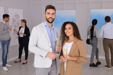Couple with glasses of champagne at exhibition in art gallery