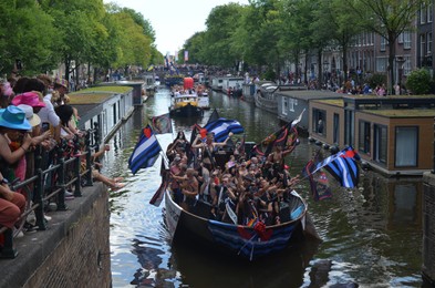 AMSTERDAM, NETHERLANDS - AUGUST 06, 2022: Many people in boats at LGBT pride parade on river