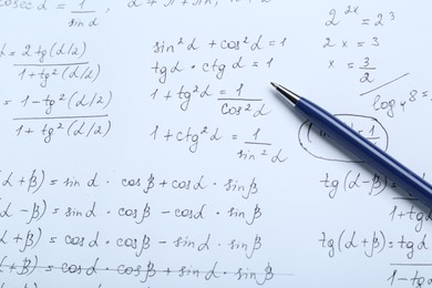 Photo of Sheet of paper with different mathematical formulas and pen, top view