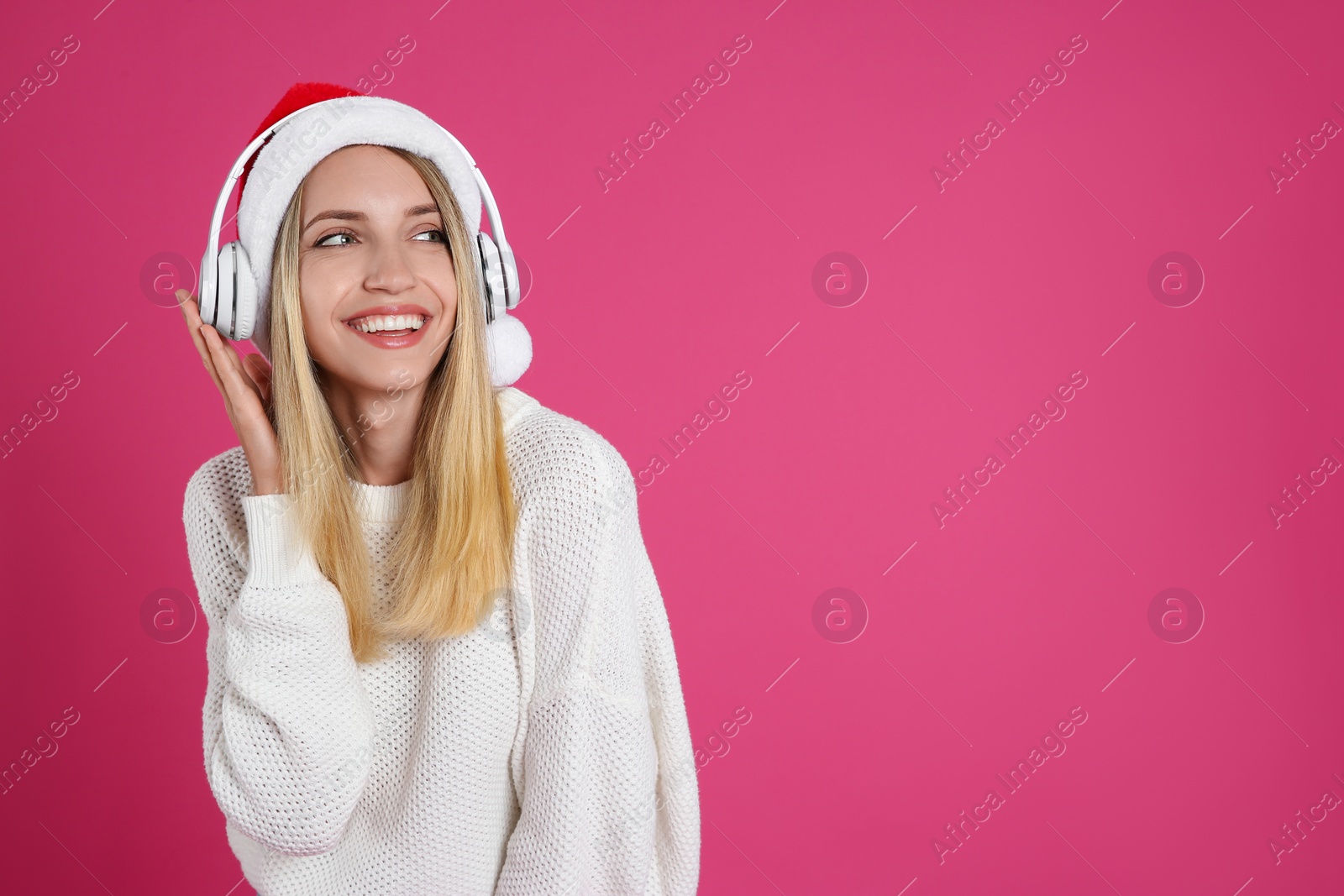 Photo of Happy woman with headphones on pink background, space for text. Christmas music