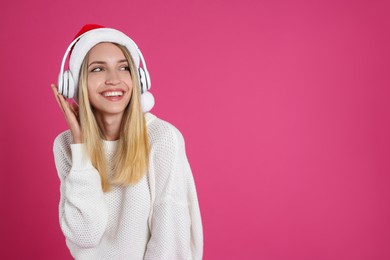 Happy woman with headphones on pink background, space for text. Christmas music