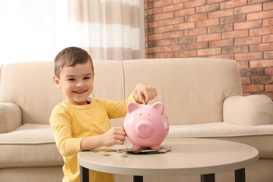Little boy with piggy bank and money at home