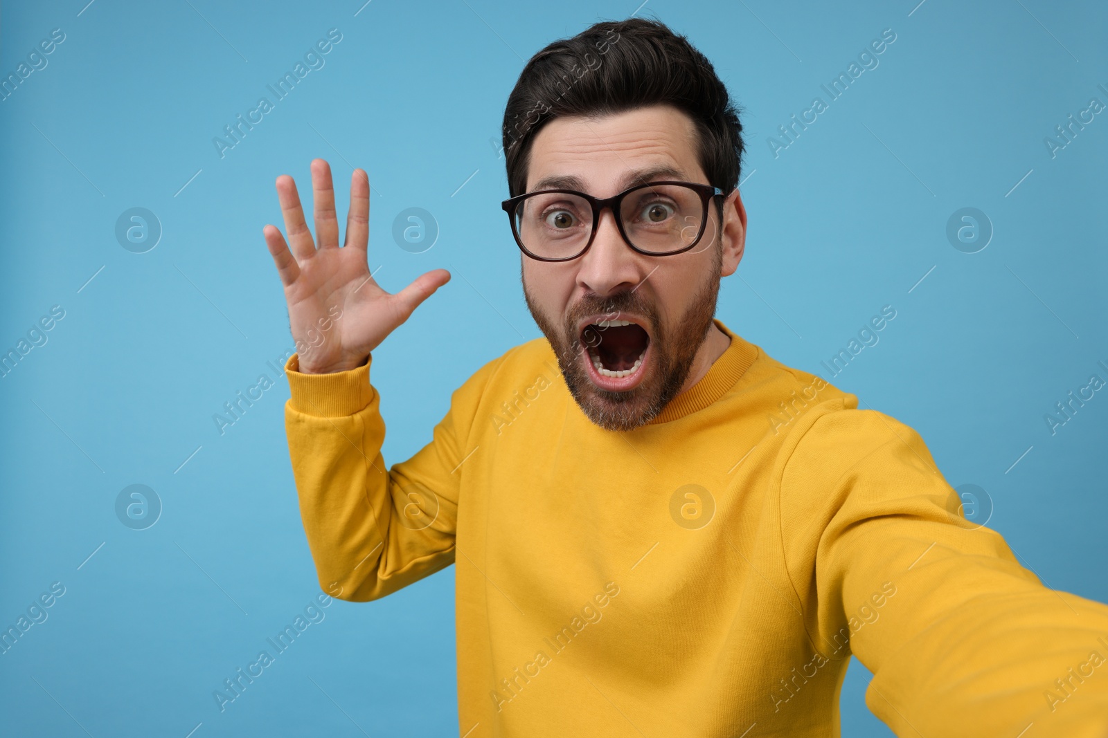 Photo of Surprised man taking selfie on light blue background