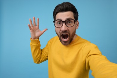 Photo of Surprised man taking selfie on light blue background