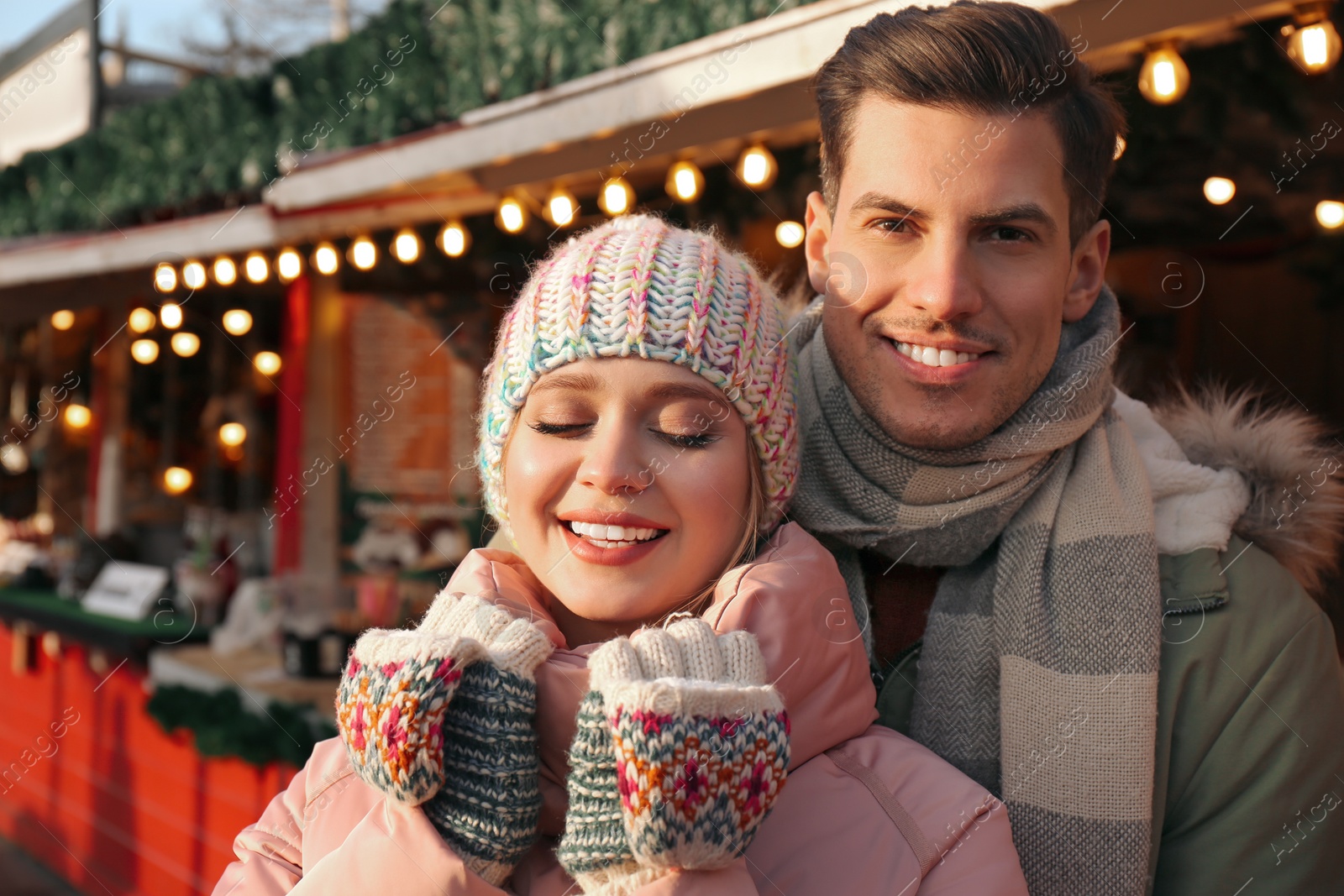 Photo of Happy couple in warm clothes at winter fair. Christmas season