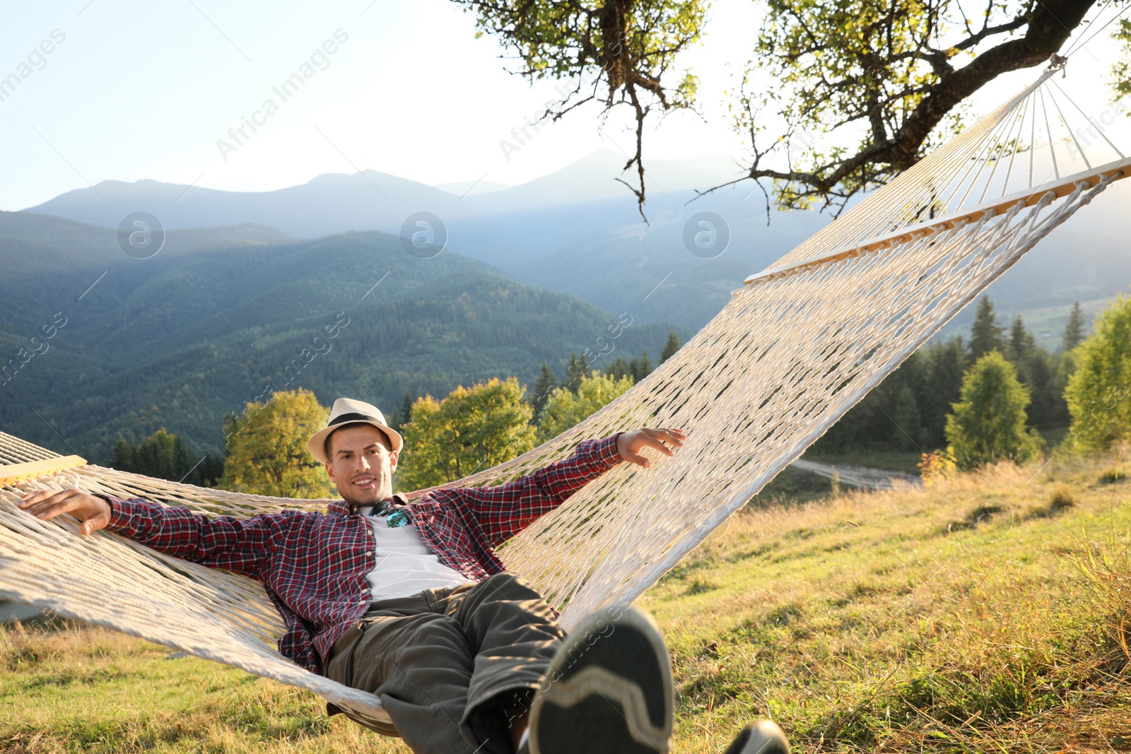 Photo of Man resting in hammock outdoors on sunny day