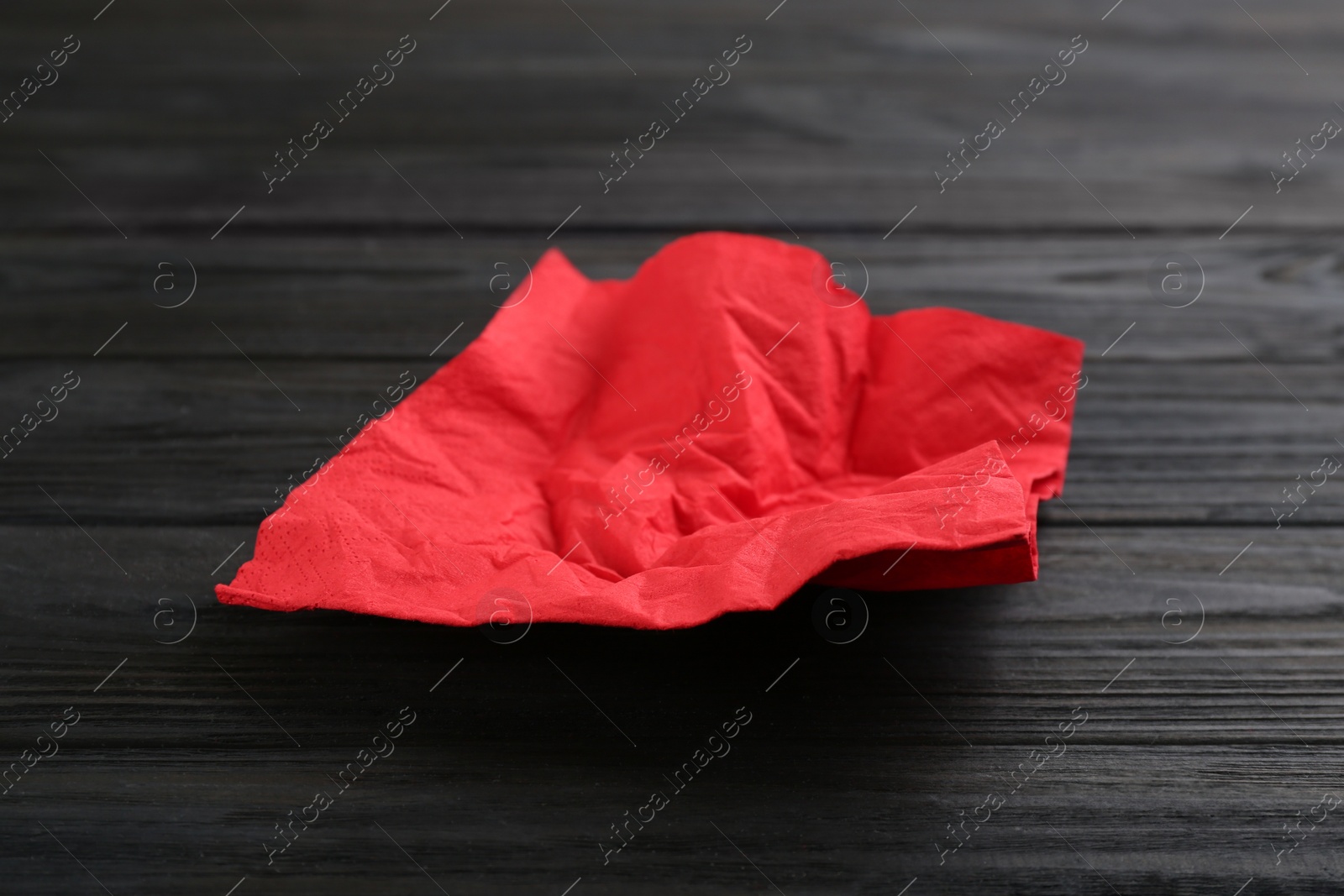 Photo of Crumpled paper napkin on wooden table. Personal hygiene