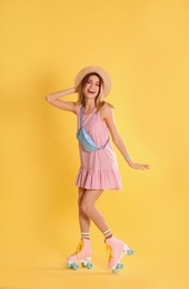 Young woman with retro roller skates on color background