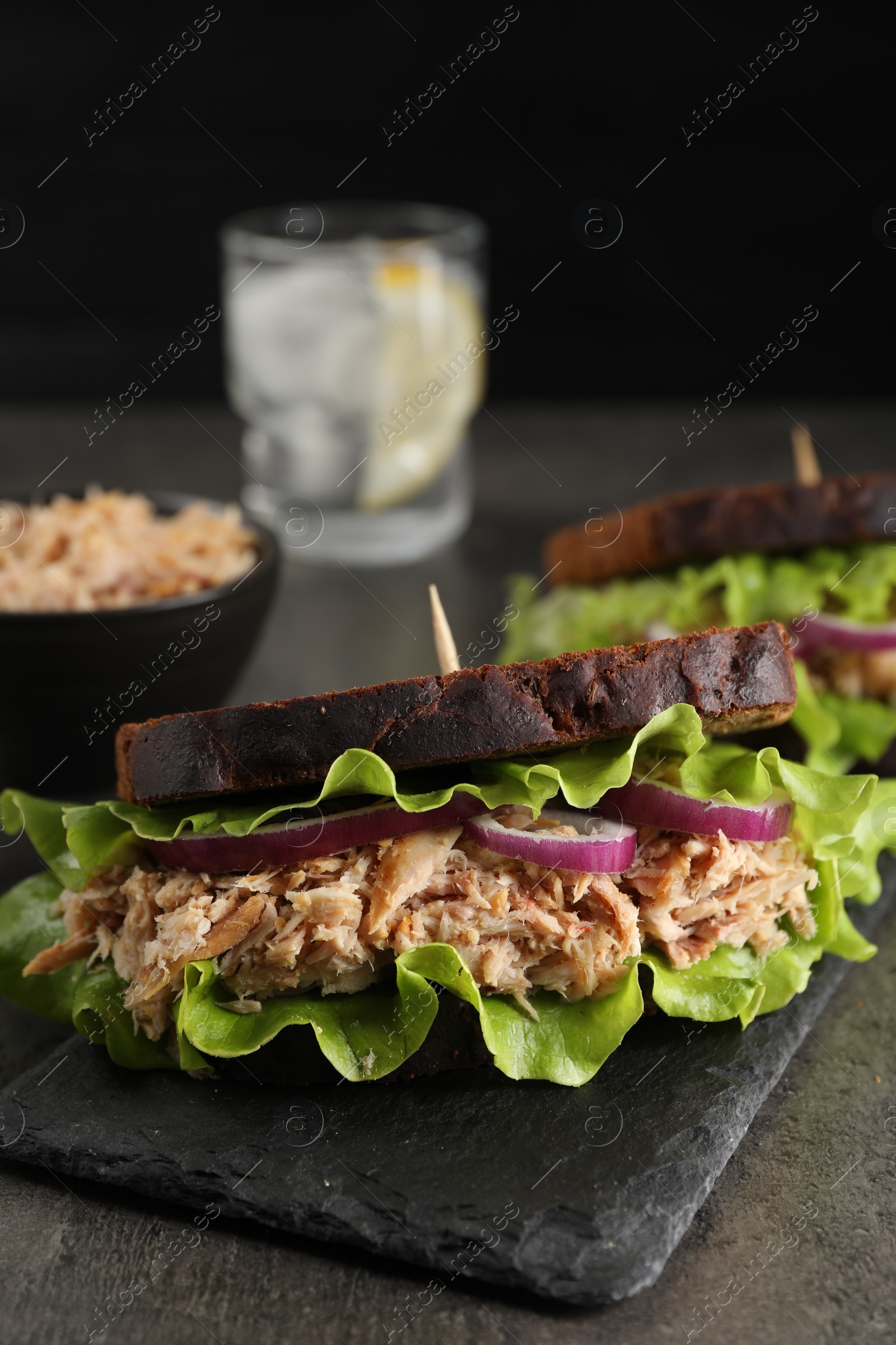 Photo of Delicious sandwiches with tuna and vegetables on light grey table, closeup
