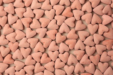 Many heart shaped vitamins for pets on beige background, flat lay