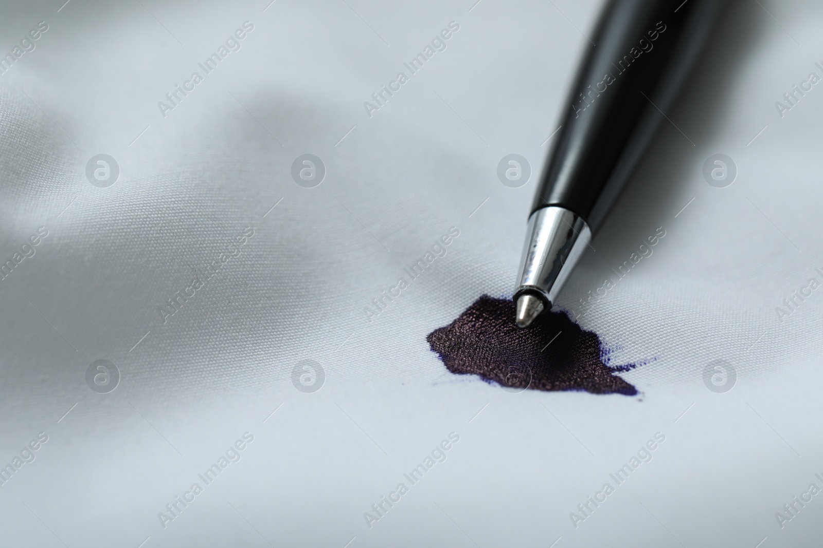 Photo of Pen and stain of black ink on white shirt, closeup. Space for text