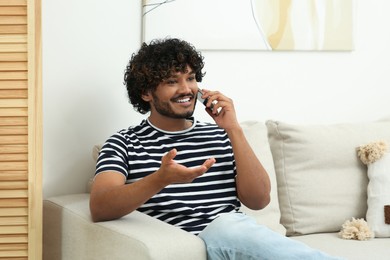 Photo of Handsome smiling man taking over smartphone in room