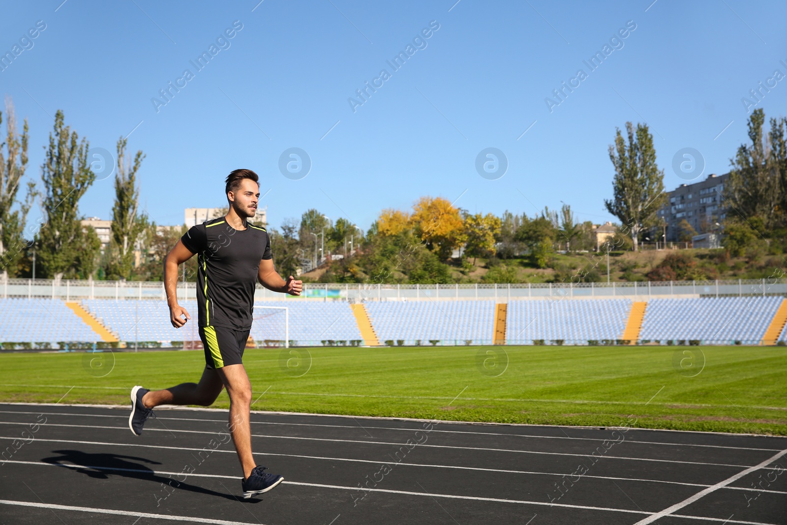 Photo of Sporty man running at stadium on sunny morning