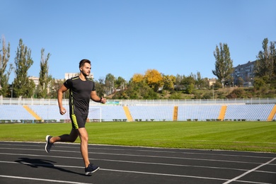 Photo of Sporty man running at stadium on sunny morning