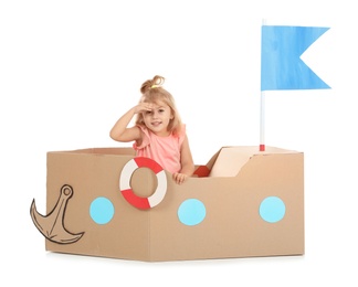 Cute little girl playing with cardboard ship on white background