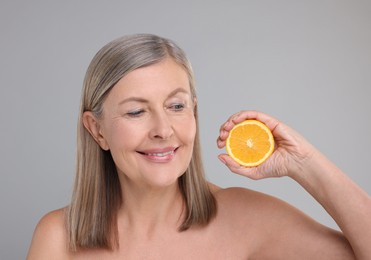 Photo of Beautiful woman with half of orange rich in vitamin C on grey background