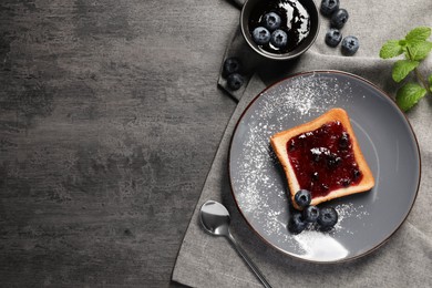 Photo of Delicious toast served with jam and blueberries on grey wooden table, flat lay. Space for text