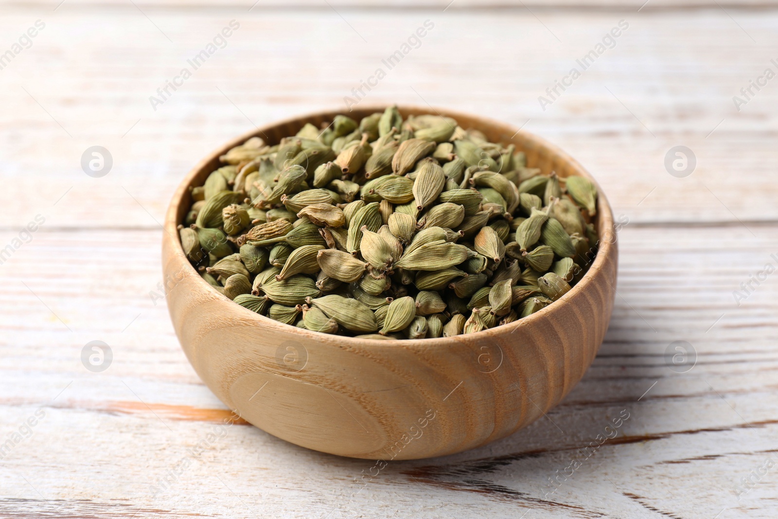 Photo of Bowl with dry cardamom on wooden table