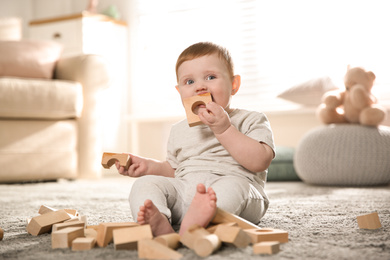 Photo of Cute baby playing with wooden blocks at home