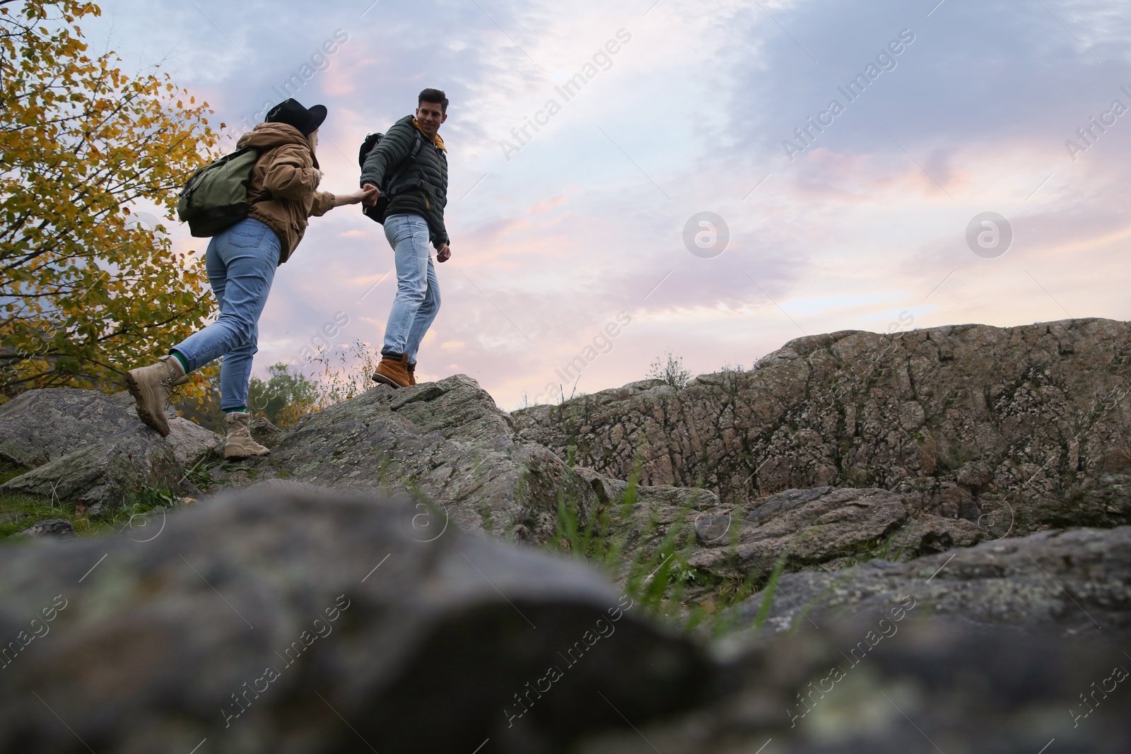 Photo of Couple of hikers with backpacks climbing up mountains