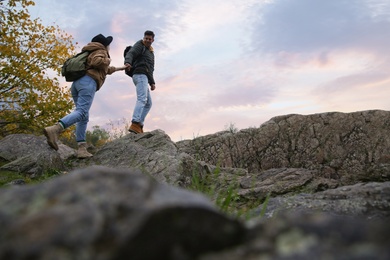 Couple of hikers with backpacks climbing up mountains