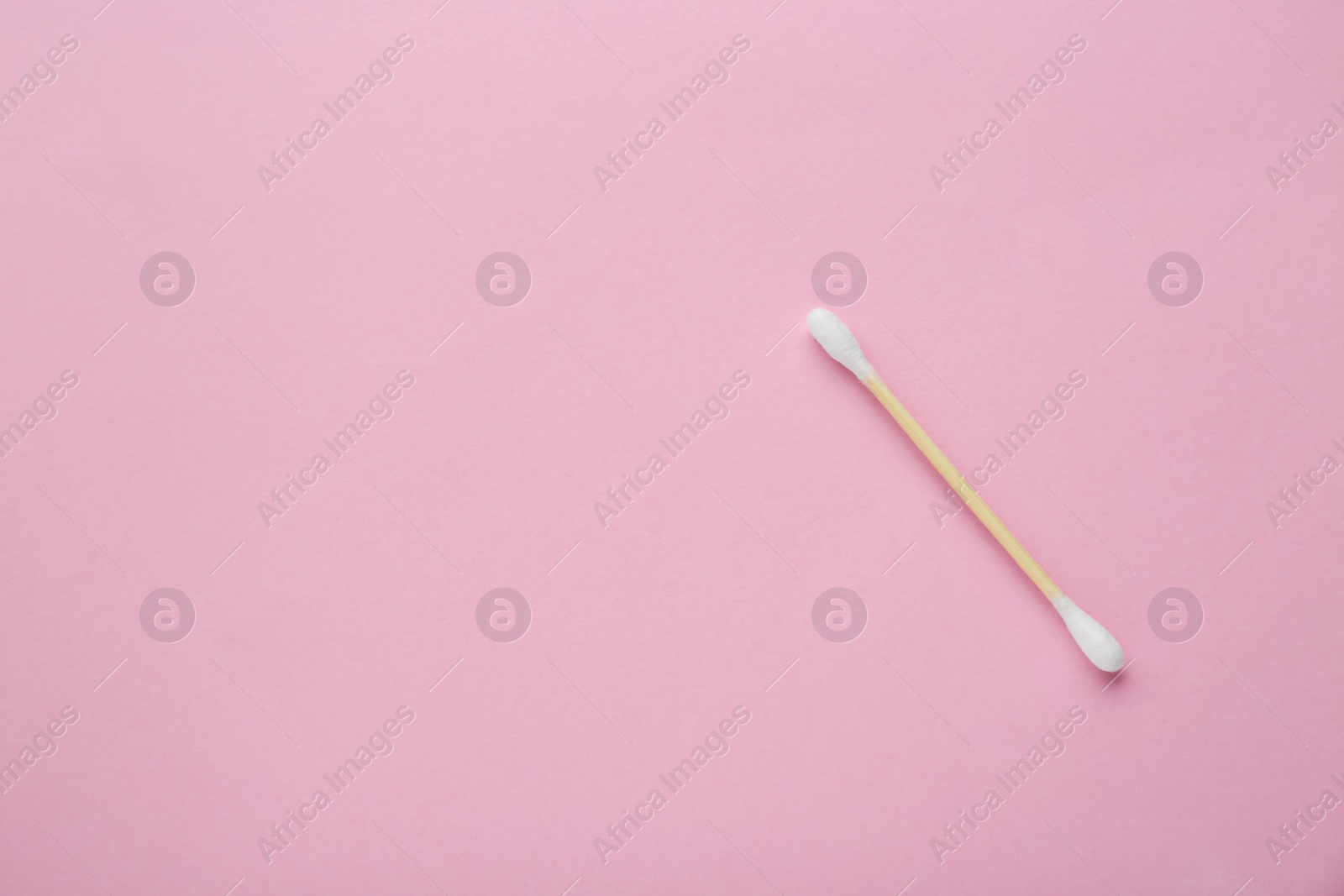 Photo of One wooden cotton bud on pink background, top view. Space for text