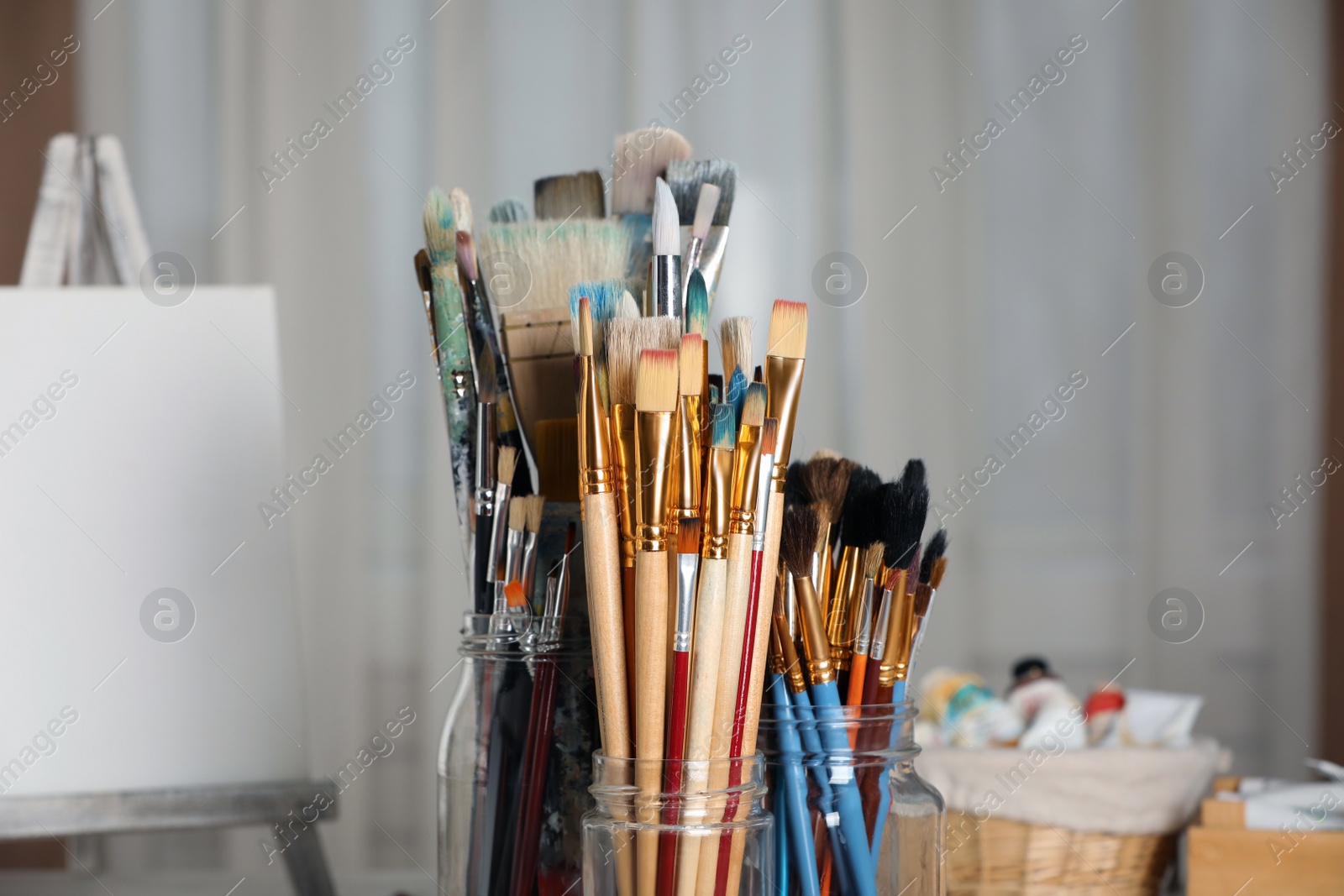 Photo of Glass jars with many different paintbrushes indoors