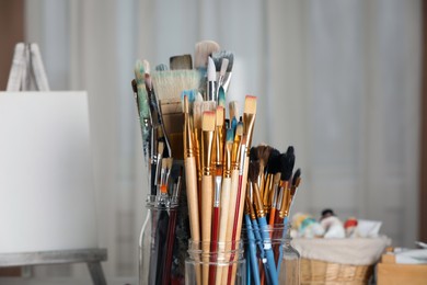 Glass jars with many different paintbrushes indoors