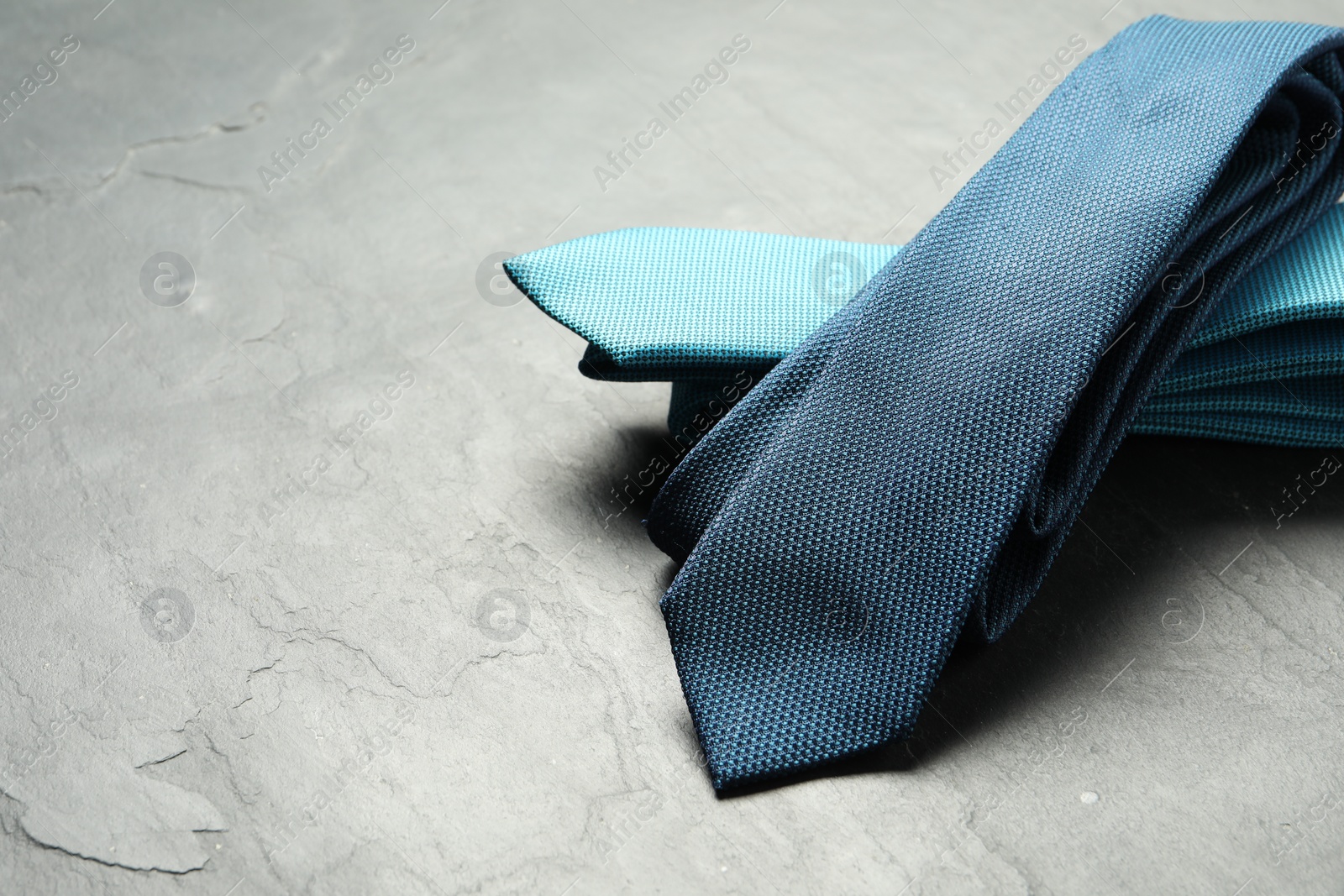 Photo of Two neckties on grey textured background, closeup. Space for text