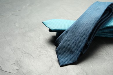 Two neckties on grey textured background, closeup. Space for text